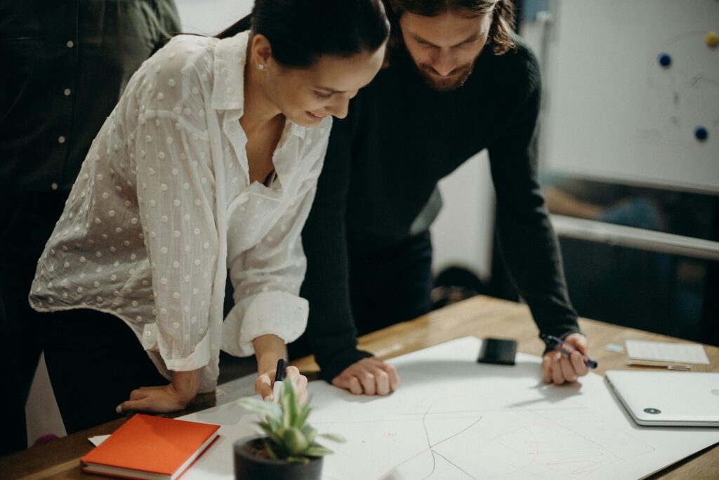 Man and woman standing over table looking at papers.