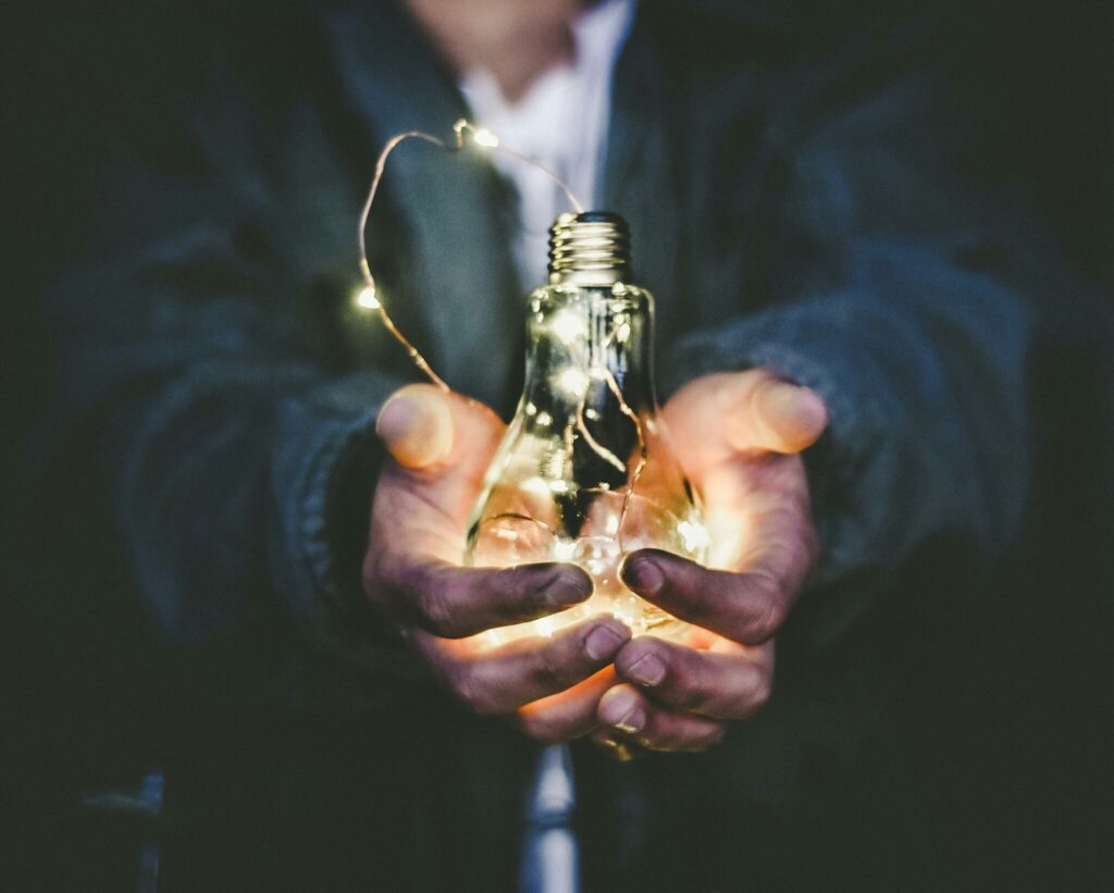 Hands cupping a glowing light bulb.