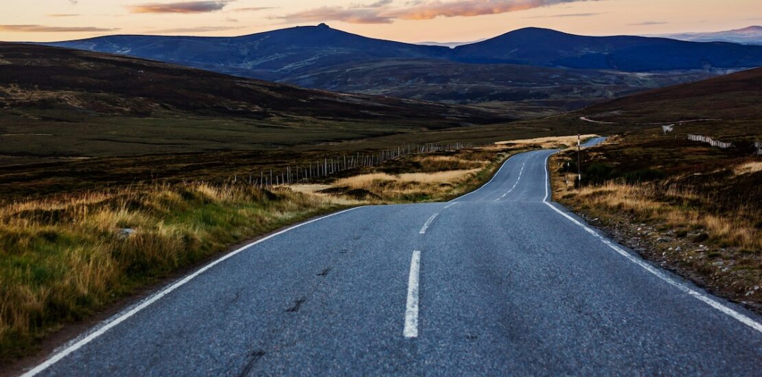 Landscape scene with road leading to mountains.